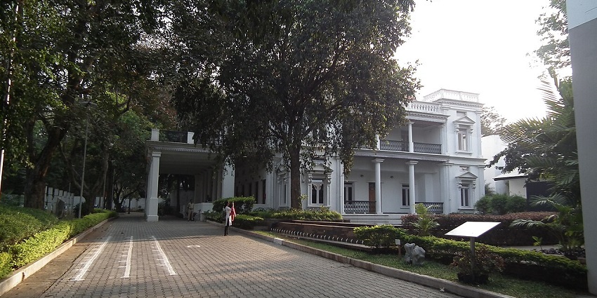 NGMA Bengaluru, with grand pillars and lush trees lining the museum’s entrance path, one of the best museums in Karnataka.