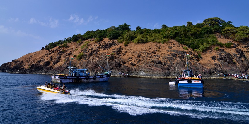 Netrani, one of the Islands in Karnataka, with two big boats parked, people on the small boat and greenery.