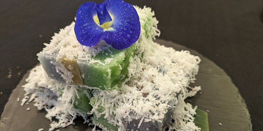 Traditional kueh topped with shredded coconut and a blue edible flower garnish, one of the best restaurants in Singapore.
