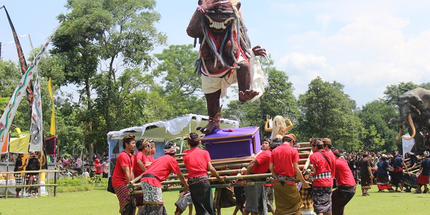 Balinese men carry vibrant ogoh-ogoh statue in festivals in Bali parade.