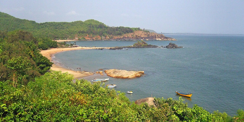 An elevated view of a sandy bay with boats and green coast, perfect for scuba diving in Karnataka.
