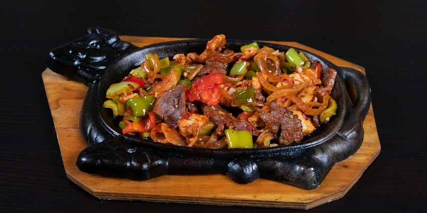 Hot and flavourful sizzlers served on a steaming plate at a cosy restaurant table.
