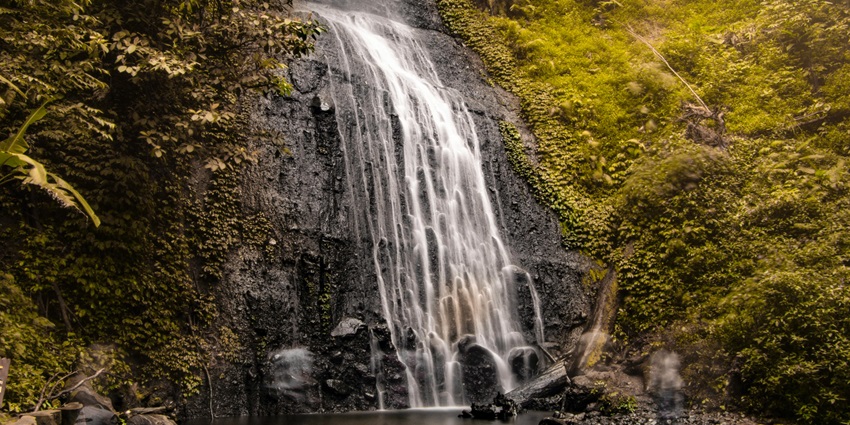 The waterfall cascades through moss-covered rocks surrounded by dense green forest, one of the best waterfalls in Darjeeling.