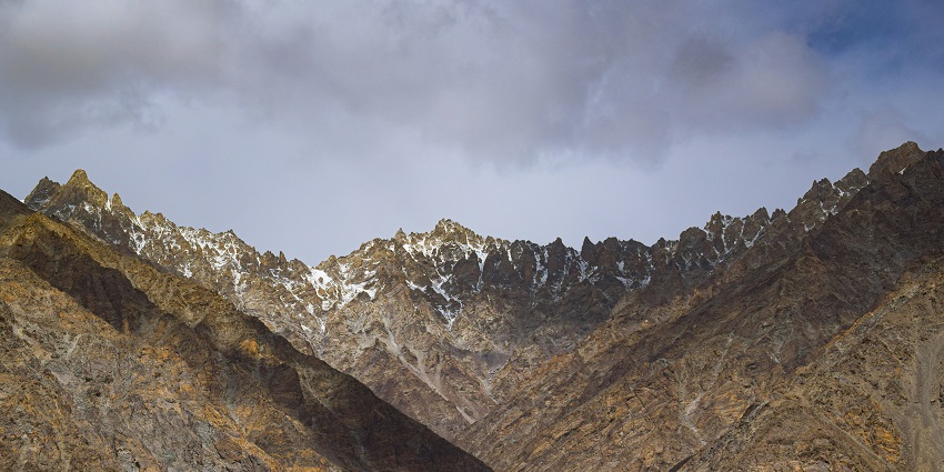 A view of a tranquil lake flanked by mountains, coarse with the hues of the atmosphere.
