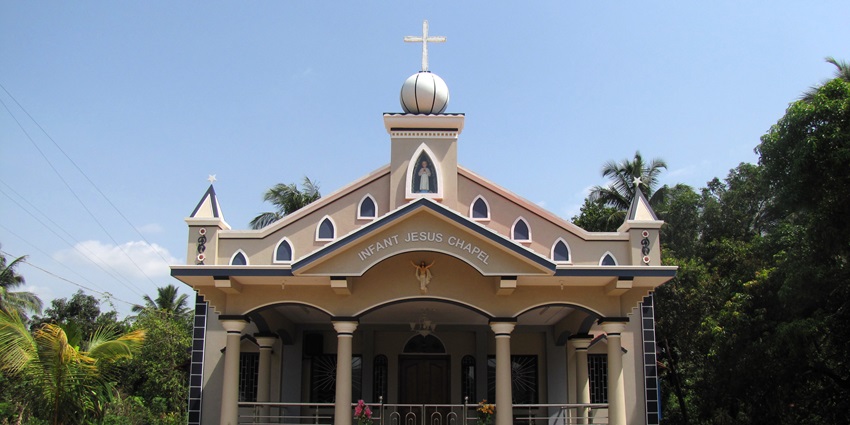 Infant Jesus Chapel at Pavoor Uliya with a Christian cross on the top of the building and greenery.