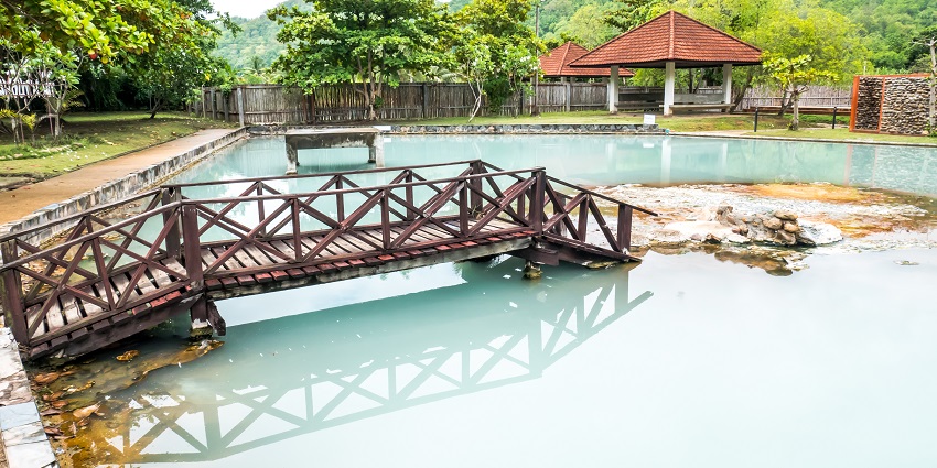 Steam rising from the warm pools at Pha Bong Hot Spring surrounded by nature.