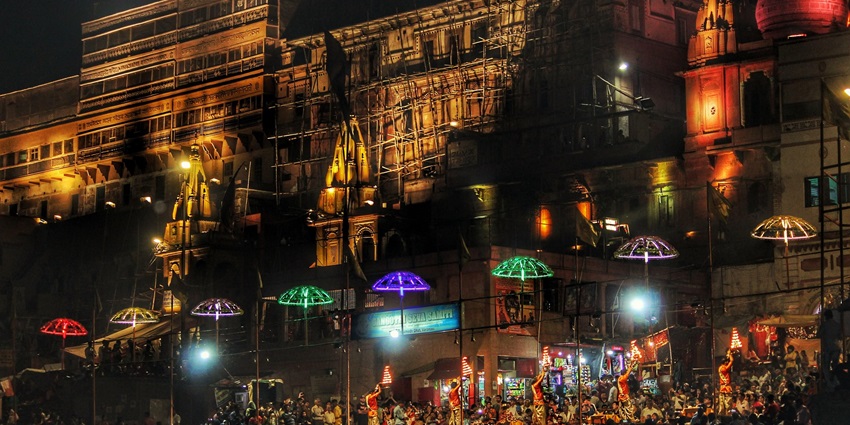 Devotees and priests performing rituals during Ganga Aarti at a Varanasi ghat for Dev Deepawali.