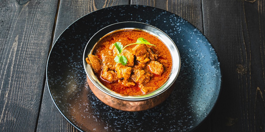 A rich, creamy butter chicken dish served in a bowl at Punjabi Kadhai restaurant.
