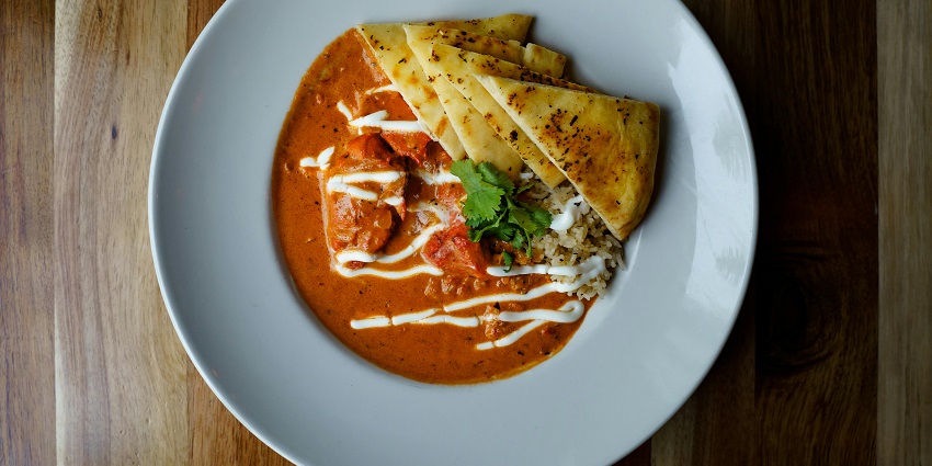 A rich, creamy butter chicken dish with naan bread, served at Punjabi Kadhai Restaurant, one of the iconic restaurants in Siliguri.
