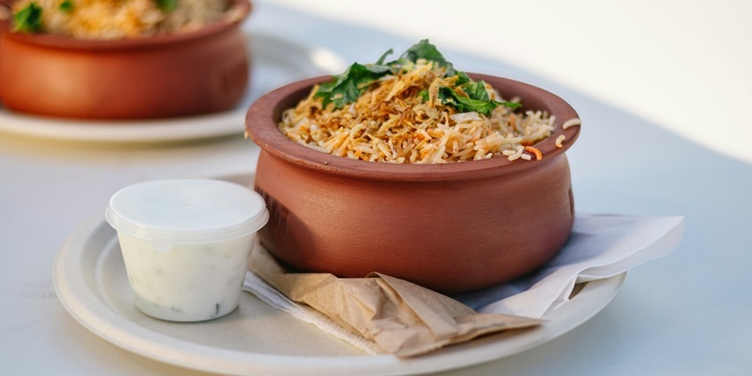 A round clay pot of rice with a bowl of raita served at Pure Heart Vegetarian Restaurant.
