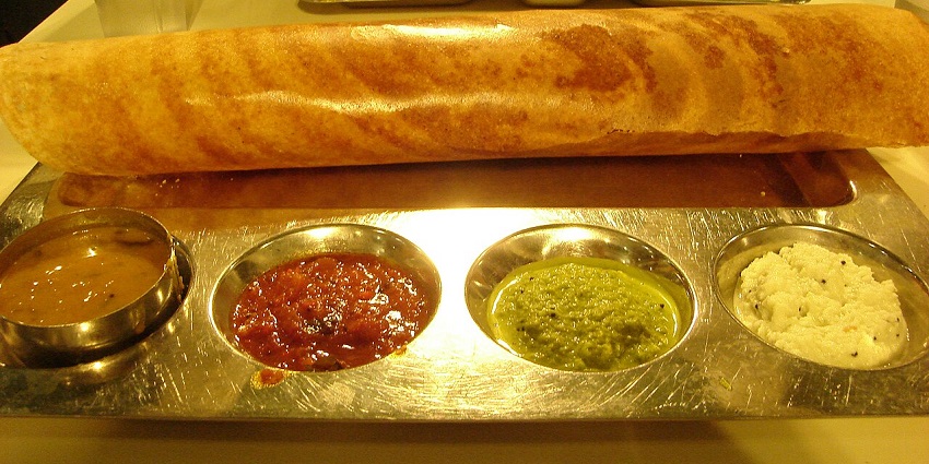 A Masala Dosa is served with sambhar, coconut chutney and some other chutneys.

