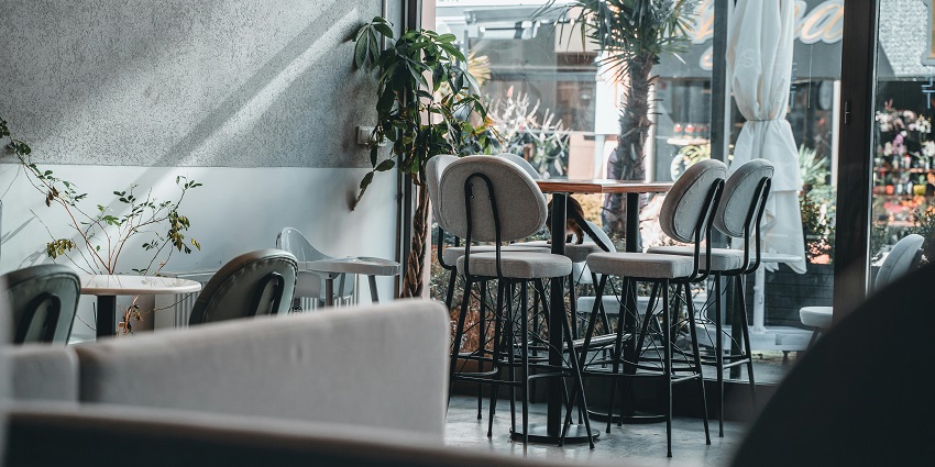 Bright café corner with high stools, indoor plants, and large windows, one of the famous restaurants in Guwahati.
