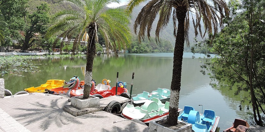 A few colorful paddle boats at Renuka Lake, surrounded by scenic hills, during festivals in Himachal Pradesh.
