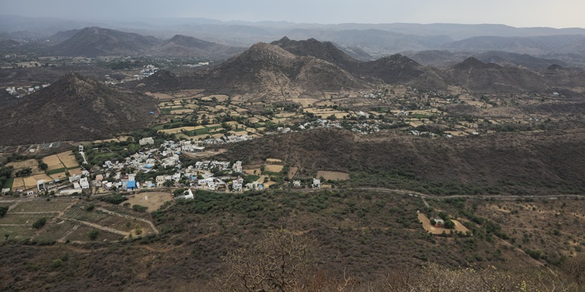 A very high-angle view of a small town nestled in a valley surrounded by rocky hills.