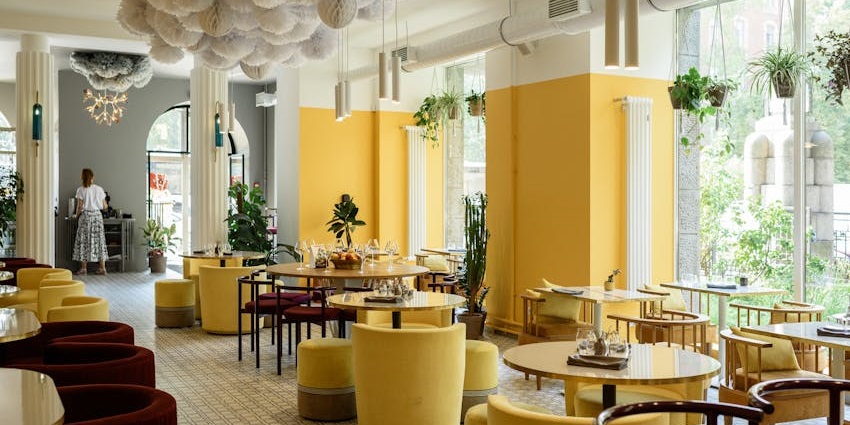 A stylish dining room with an eclectic mix of furniture, yellow walls, and unique decor at Sala, one of the famous veg restaurants in Malaysia.