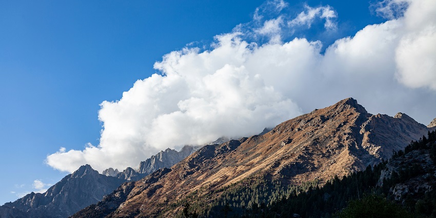 Hilltop view of Sangla Valley in Himachal Pradesh with green slopes and mountain scenery.
