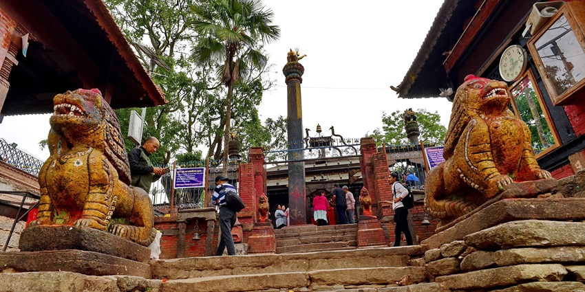 Stone lion statues guard the entrance of a historic temple with visitors climbing stairs.