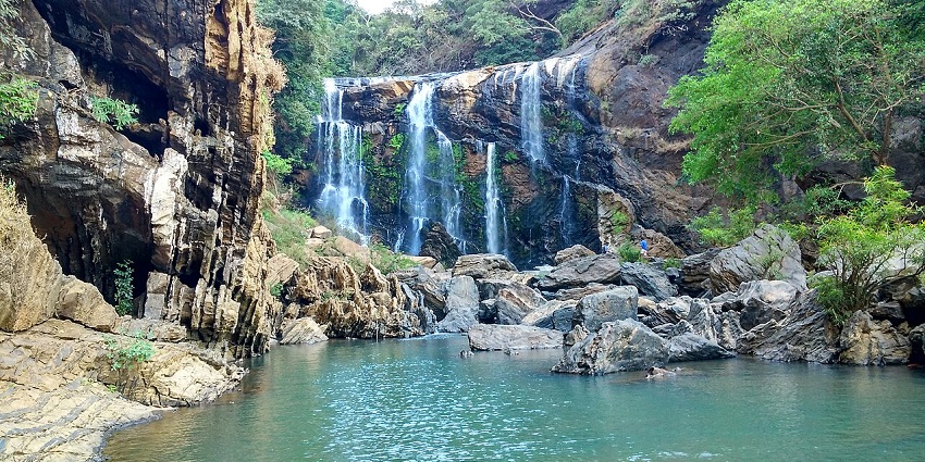A lush green forest surrounds the cascading waters of Sathodi Falls, one of the majestic waterfalls in Karnataka.
