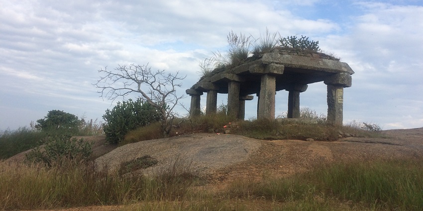 An ancient temple at the top of the Savandurga Trek is surrounded by rocky terrain and greenery.
