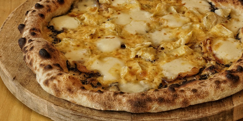 Freshly baked wood-fired pizza served hot on a plate at Seasons Pizzeria.
