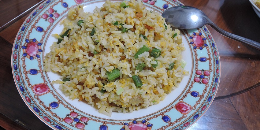 A homemade plate of fried rice with veggies like chopped beans is served at a table at at one of the vegetarian restaurants in Havelock Island.