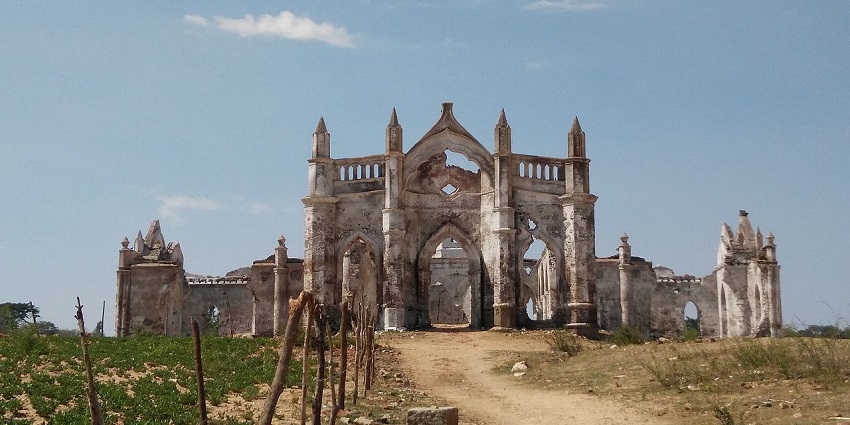 An abandoned church half-buried in a reservoir, ruined arches extending into water.
