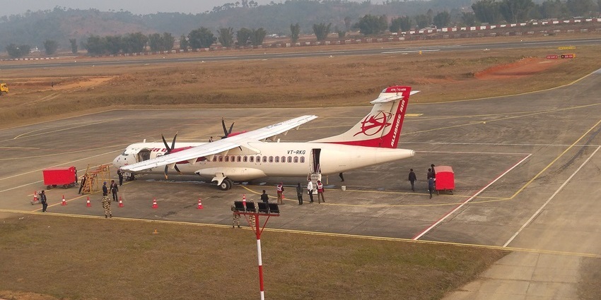 ATR72 aircraft on the tarmac at Shillong Airport with passengers boarding and hills in view.