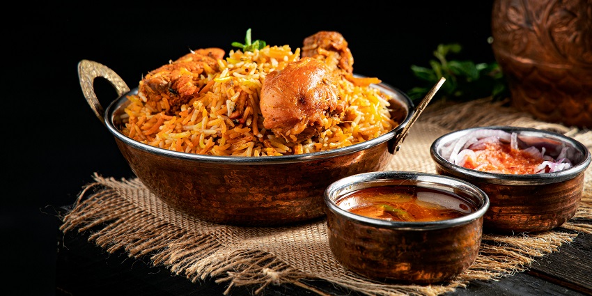A plate of chicken biryani served with salad at a rooftop restaurant setting.
