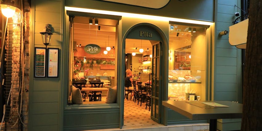 Warmly lit café entrance with seating and bakery display at Sixty Vines, one of the restaurants in Woodlands.