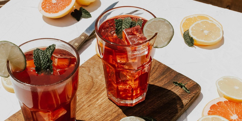 Two glasses of kombucha with ice and citrus garnish at a rooftop lounge table.
