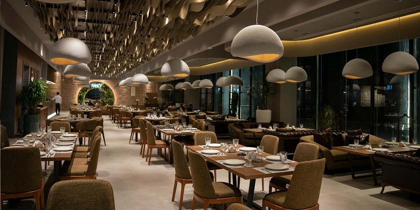 Elegant restaurant with warm pendant lights, set tables, and a modern wave ceiling design among the multiple restaurants in Havelock Island.
