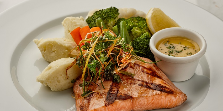 White plate topped with fish and vegetables served at a steakhouse in KL.