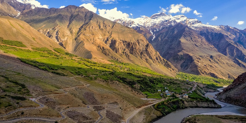 Scenic view of Suru Valley in Ladakh with green meadows, mountains, and a flowing river.
