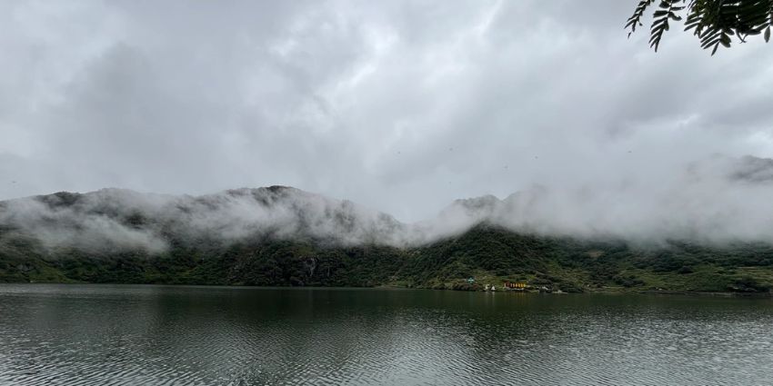 A serene view of the shimmering waters of Tsomgo Lake surrounded by majestic peaks.