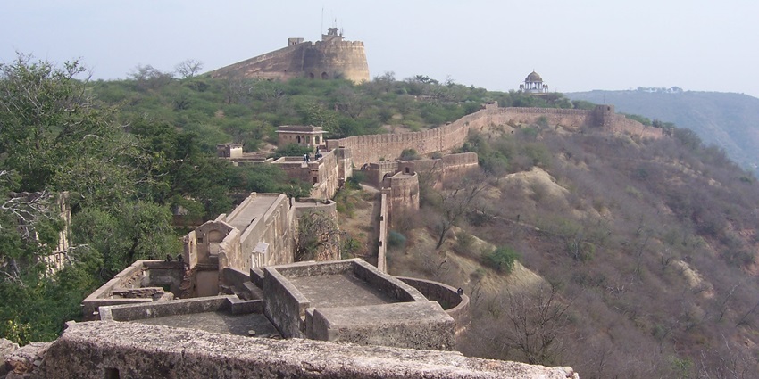 Taragarh fort in Ajmer with old architectural walls, green trees and dried trees on the other side.