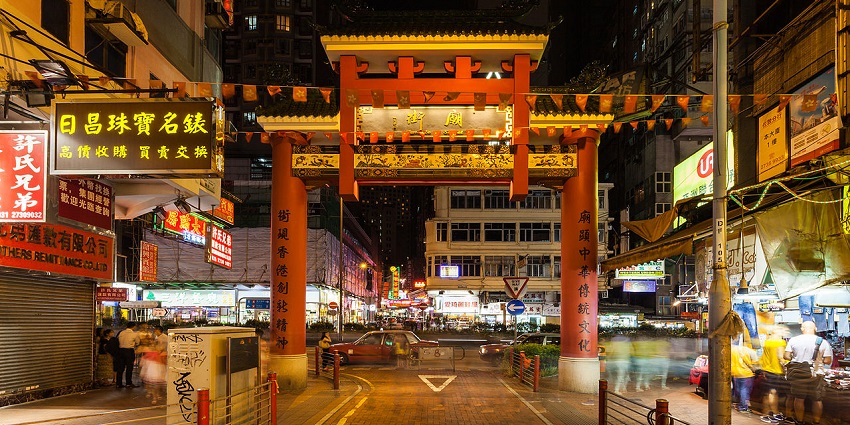 A nighttime view of the entrance of the Temple Street Night Market in Hong Kong.
