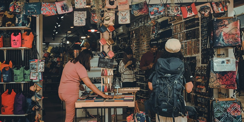 Clothes and hats are displayed at a vibrant outdoor market stall.
