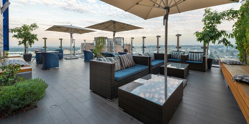 Rooftop lounge with wicker seating, striped cushions, umbrellas, and panoramic city views, one of the restaurants in Port Blair.