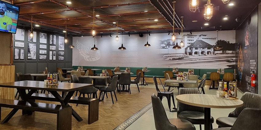 A large, modern restaurant dining room with many tables, booths, and eclectic lighting.

