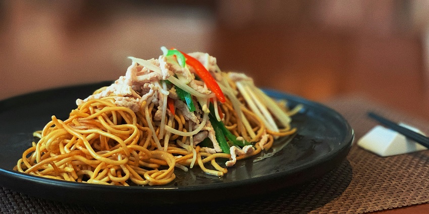Noodles served on a black plate at The DECK restaurant with elegant presentation.
