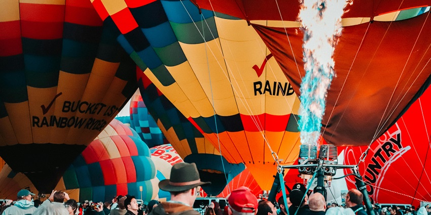 Hot air balloons preparing for launch at Albuquerque International Balloon Fiesta with flames and crowd.