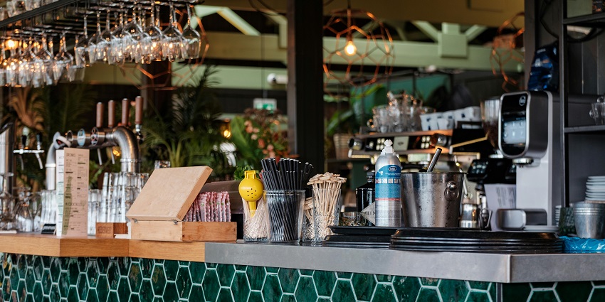 Barista at Café Lux serving a customer at a modern counter with coffee sacks and a menu in one of the cafes in Gangtok.
