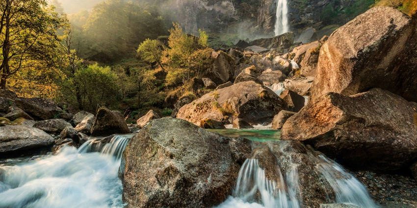 Tiger Falls in Chakrata, a tall waterfall surrounded by dense forest and rocky cliffs.