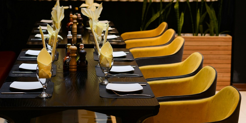 A long table with yellow chairs and black tablecloths at Tom & Jerry’s, one of the best restaurants in Darjeeling..
