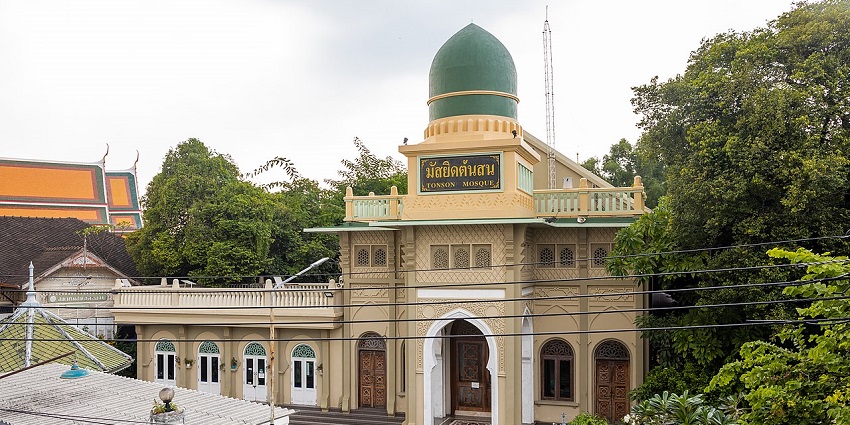 Ton Son Mosque in Bangkok features a cream facade, an arched doorway, and a large green dome.
