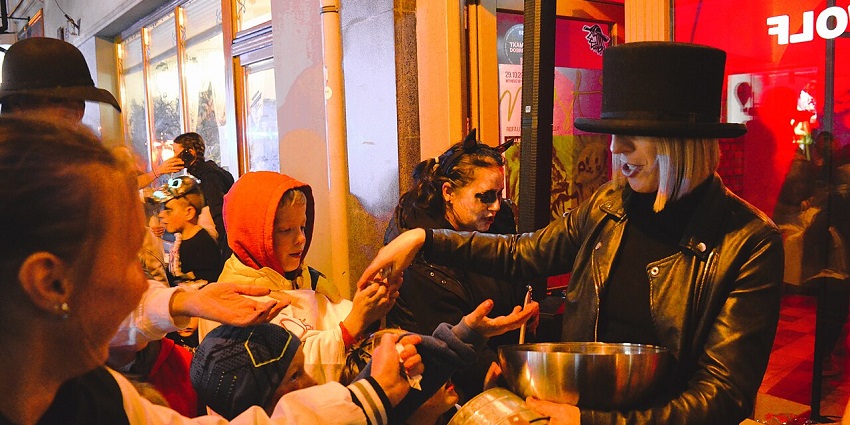 Kids dressed in spooky costumes during a trick-or-treating ceremony arranged on a street, similar to what's expected in Halloween day 2025.