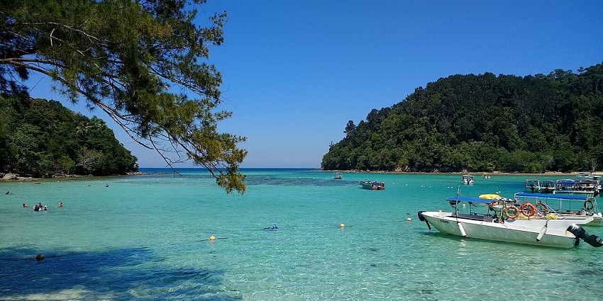 Boats docked and people were swimming in the bright water of Sapi Island in the marine park.
