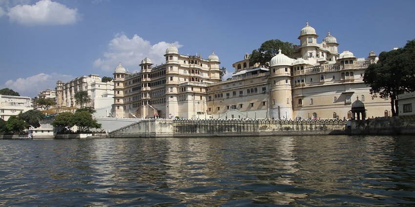 Scenic view of Lake Pichola in Udaipur with palaces and Aravalli hills reflecting in the calm waters.