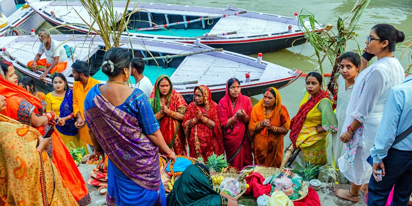 People celebrate and perform rituals of Chhath Puja at the Varanasi ghats with boats docked.