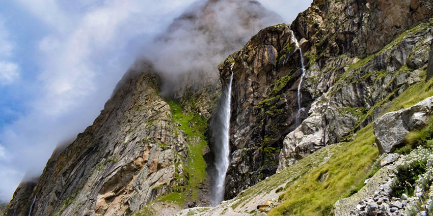 Vasudhara Falls in Uttarakhand plunges as a thin white stream between towering rocky cliffs, one of the best waterfalls in Uttarakhand.